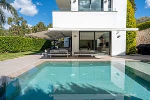 Exterior view of the villa featuring a saltwater infinity pool, covered terrace, and direct access to the living area.