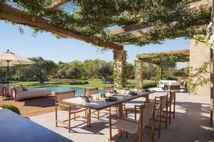 Render of a new-build finca with gabled brick facades, stone base and green-roofed carport pergolas