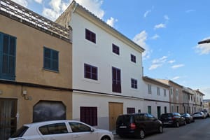 Exterior view of a multi-story townhouse in Campos featuring a white rendered facade, wooden shutters, and street parking.