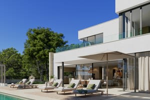 Modern white villa exterior featuring a stone-paved terrace with lounge chairs beside an outdoor swimming pool.