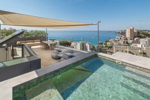 Elevated view of a penthouse terrace featuring a tiled plunge pool, outdoor dining area under a shade sail, and sea horizon.