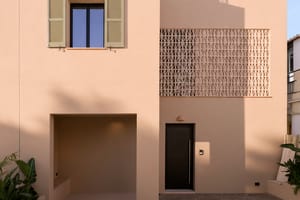 Front view of a two-story beige townhouse in Genova with geometric terracotta latticework and a covered entrance alcove.