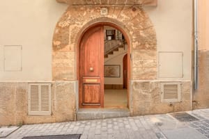 An arched timber front door set within a traditional natural stone facade on a cobblestone Old Town street.