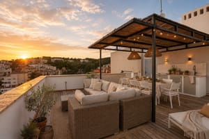 Rooftop terrace with wicker sofa, dining area, and outdoor kitchen at sunset in San Agustin.