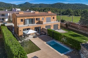 Aerial view of a Mediterranean townhouse with a terracotta roof, private pool, and landscaped garden against a mountain backdrop.