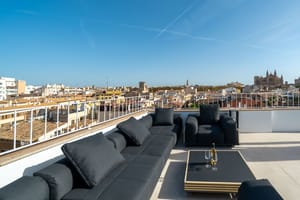 Modern black lounge furniture on a sun-drenched rooftop terrace overlooking Palma Old Town and the Cathedral.