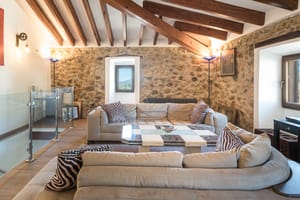 Living room with vaulted wood-beamed ceiling, stone feature wall and sectional sofa