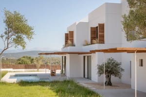 Modern white house featuring wooden shutters and a swimming pool with views of the distant mountains and green landscape.