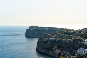 Aerial view of rocky coastline and cliffs meeting the Mediterranean sea in Port d'Andratx during daylight.