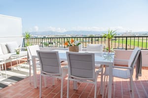 Rooftop terrace in El Molinar featuring a white dining set and outdoor sofa overlooking distant mountains under a clear sky.