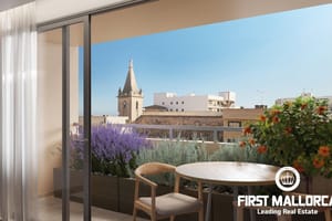 A modern apartment terrace featuring a small wooden table and chair, looking out over the Santa Catalina cityscape under a clear blue sky.