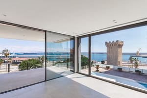 Light-filled corner living space with floor-to-ceiling glass on two elevations framing Palma harbour and open sea