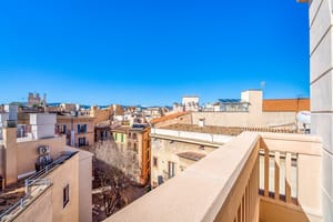 An elevated view from a rooftop terrace looking out over the densely packed stone buildings and terracotta roofs of an Old Town.