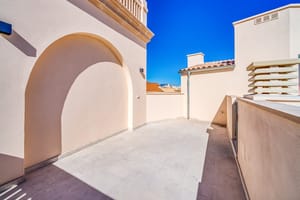 Empty rooftop terrace in Old Town with beige stucco walls, a large arched niche, and views toward traditional tiled rooftops.