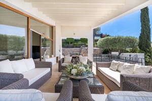 Covered outdoor terrace with rattan sofa set and far-reaching sea and mountain views at a villa in Son Vida, Mallorca