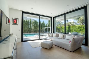 Living area with grey sectional sofa and sliding glass doors opening onto the swimming pool.