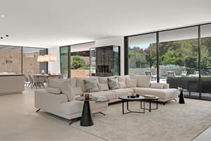 Open-plan living room with large sectional sofa, dining table and floor-to-ceiling glazing to garden
