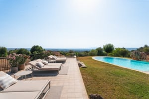 Terraza de piscina en Manacor con tumbonas sobre pavimento hacia el paisaje montañoso lejano.