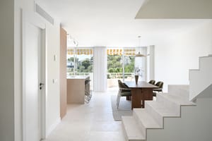 Living room with linen sofa, walnut coffee table, and floor-to-ceiling glazing framing seaview terrace