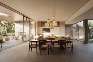 Dining room with long dark wooden table and woven chairs, glass walls opening to a lush garden, and a modern tiered chandelier.