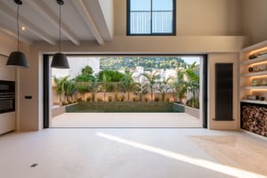 Open-plan living space featuring full-width sliding doors that lead to a private terrace with a pool and mountain views.