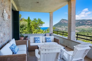 Large covered terrace with fireplace, multiple seating zones, and uninterrupted view across forested valley to distant mountains