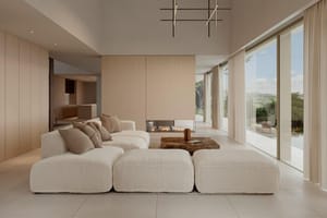 Double-height living room with a suspended fireplace and pool views