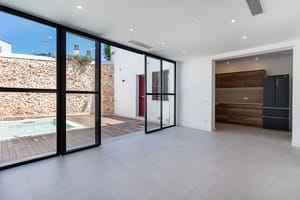 Modern open-plan living room with large floor-to-ceiling sliding glass doors opening onto a stone-walled terrace with a plunge pool.