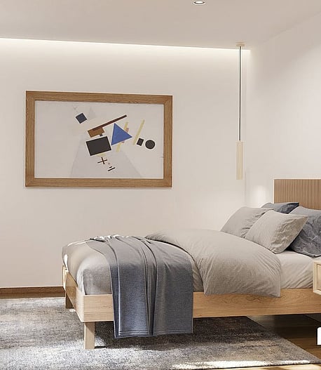 Modern bedroom featuring a wooden bed frame, slatted headboard, plush grey rug, and minimalist lighting against white walls.