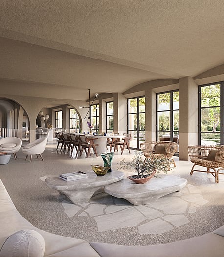 Spacious living and dining room with arched walls, light stone floors, neutral upholstered sofas, and large glass doors.