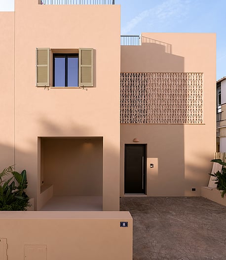 Front view of a two-story beige townhouse in Genova with geometric terracotta latticework and a covered entrance alcove.