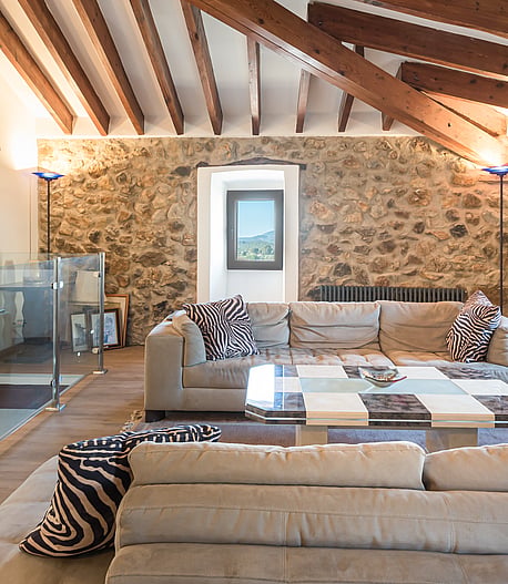 Living room with vaulted wood-beamed ceiling, stone feature wall and sectional sofa
