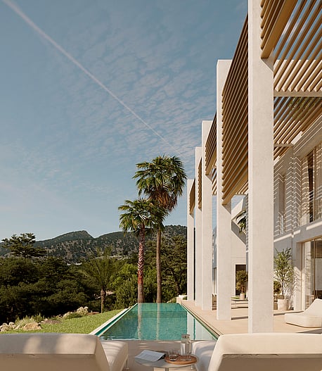Rectangular turquoise lap pool beside a white modern villa with wooden pergolas, palm trees, and mountain views.