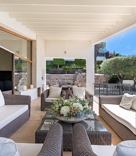 Covered outdoor terrace with rattan sofa set and far-reaching sea and mountain views at a villa in Son Vida, Mallorca