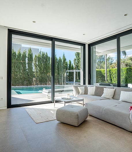 Living area with grey sectional sofa and sliding glass doors opening onto the swimming pool.
