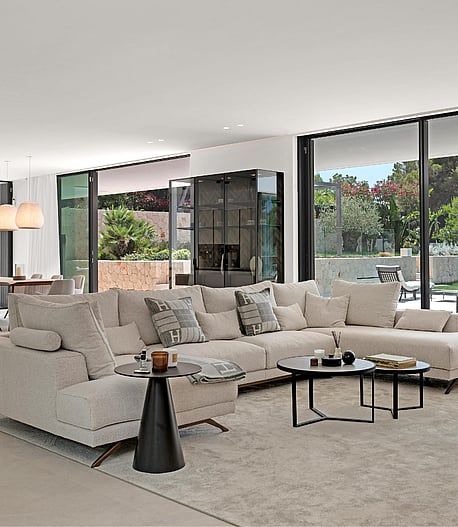 Open-plan living room with large sectional sofa, dining table and floor-to-ceiling glazing to garden