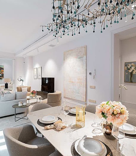 Bright open-plan living area featuring a modern dining set with upholstered chairs and a sofa area with neutral textiles.