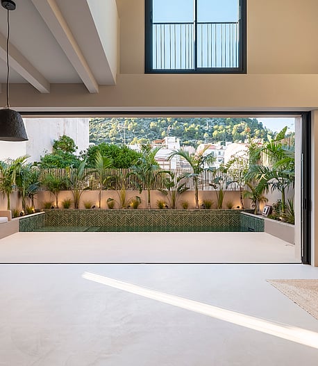 Open-plan living space featuring full-width sliding doors that lead to a private terrace with a pool and mountain views.