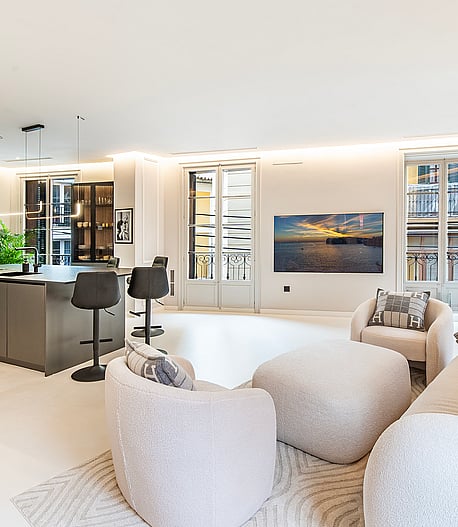Modern open-plan living space with a dark island kitchen, textured white seating, and high ceilings in an Old Town apartment.