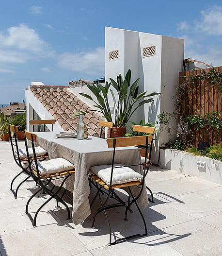 Rooftop terrace featuring an outdoor dining table, potted greenery, and views towards the Santa Eulàlia Church tower.