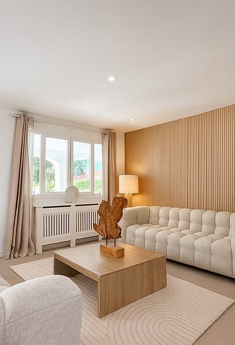 Living room with two cream bouclé sofas, wooden slat feature wall, low oak coffee table and tiled flooring