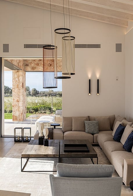 Living room with high vaulted ceiling, neutral sofa, and large glass doors opening to a terrace with mountain views.