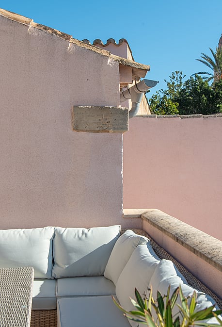 Outdoor terrace featuring exterior sofas, soft pink walls, and views towards the church tower in Calvià.