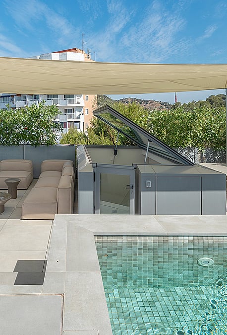 Rooftop terrace featuring a tiled swimming pool, modular beige sofa, dining area, and a beige shade canopy under clear skies.