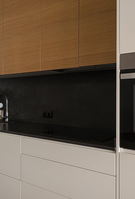 Modern kitchen featuring matte beige lower cabinets, wood veneer upper cabinets, and a black stone countertop.
