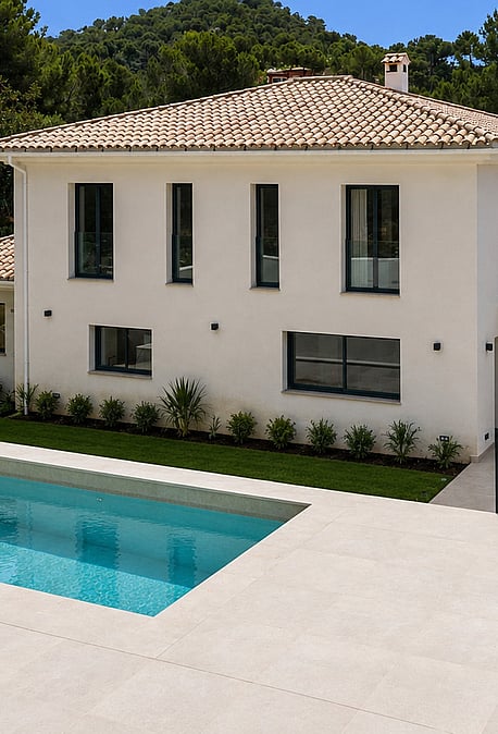 Exterior view of a white villa with clay-tiled roof, rectangular pool, and manicured lawns in Santa Ponsa.