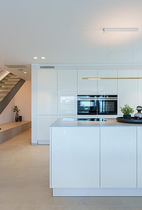 Cocina blanca moderna con isla y escalera abierta con iluminación LED integrada en un piso luminoso.