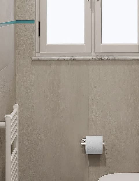 Interior view of a minimalist bathroom featuring grey stone tiles, a white wall-mounted toilet, and a small window.