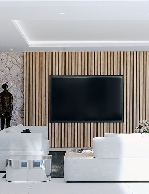 A modern living area featuring a white sofa, a slatted oak wall with a television, a rough stone accent wall, and a home bar.
