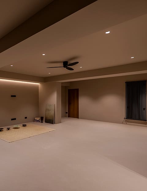 A large empty interior room with taupe walls, warm recessed spotlighting, a dark ceiling fan, and integrated LED strips.